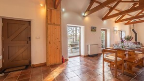 Eine geräumige Küche mit einem großen Holztisch und Stühlen, ein Fliesenboden und eine rustikale Holzaussparung an der Decke.
