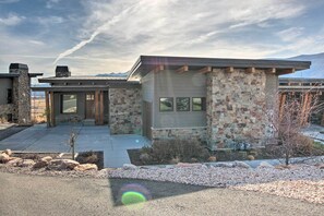 Una casa moderna con fachada de piedra y madera, un garaje y un jardín cuidado.