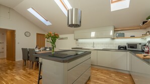 Una cocina moderna con una isla central, suelo de madera y tragaluces.