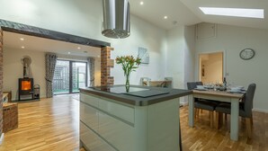Una cocina moderna con una isla central, estufa integrada y un comedor con mesa y sillas.