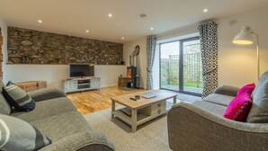 Una sala de estar moderna con una pared de piedra, una chimenea y un ventanal con cortinas estampadas.