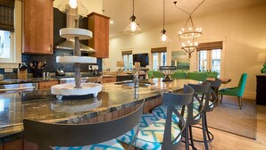 A spacious kitchen with a central island, bar stools, and modern lighting fixtures. - Sweet Seas Cottage - South of 30A! Close to the Beach, Coquina Pool & Town Center! (Rosemary Beach)