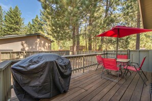 A covered outdoor deck with a barbecue grill, red chairs, and a red umbrella. - Red Fir Retreat - Completely Remodeled! - Vogtlin (Truckee)
