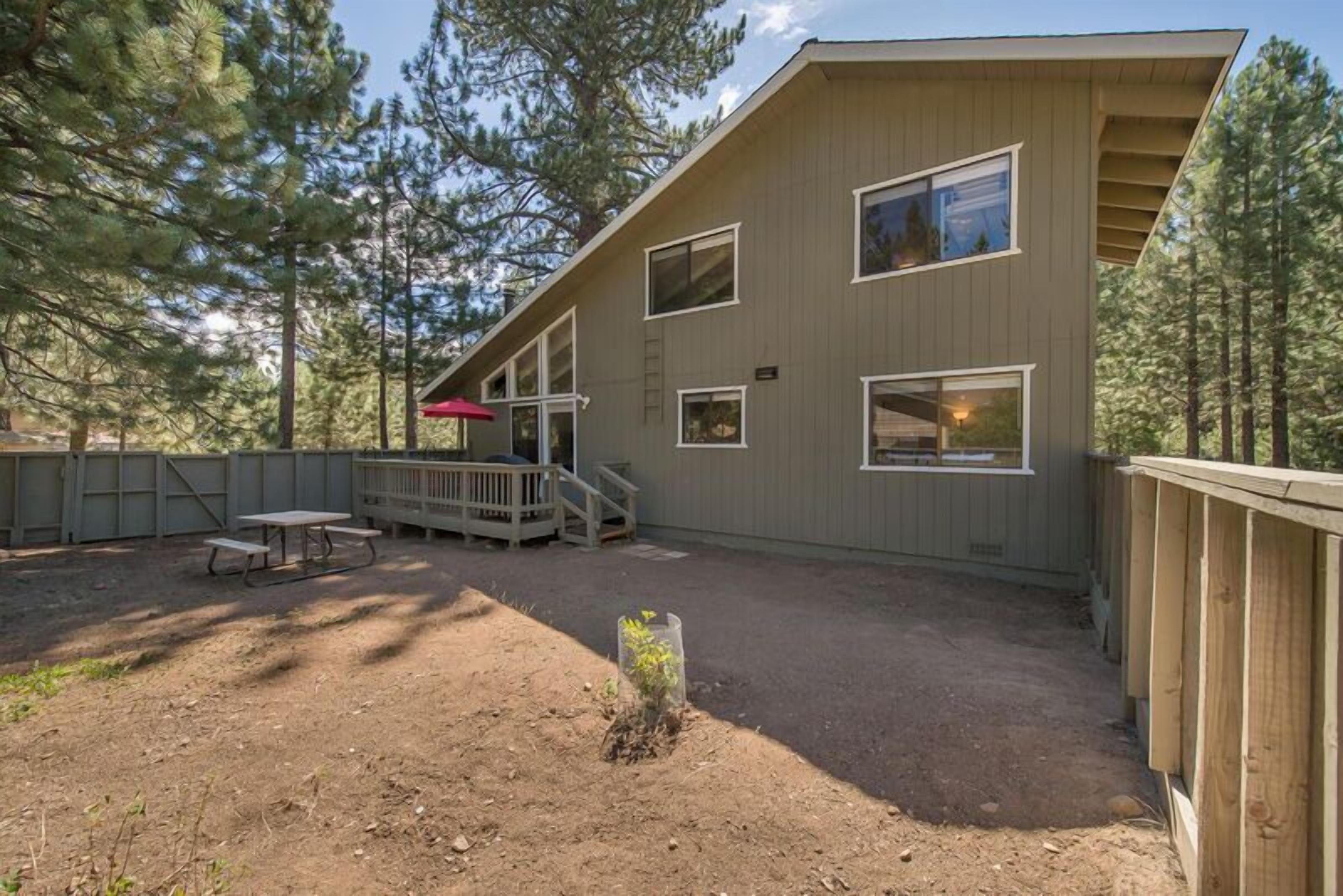 A modern building with a sloped roof, multiple windows, and a wooden deck with a picnic table.