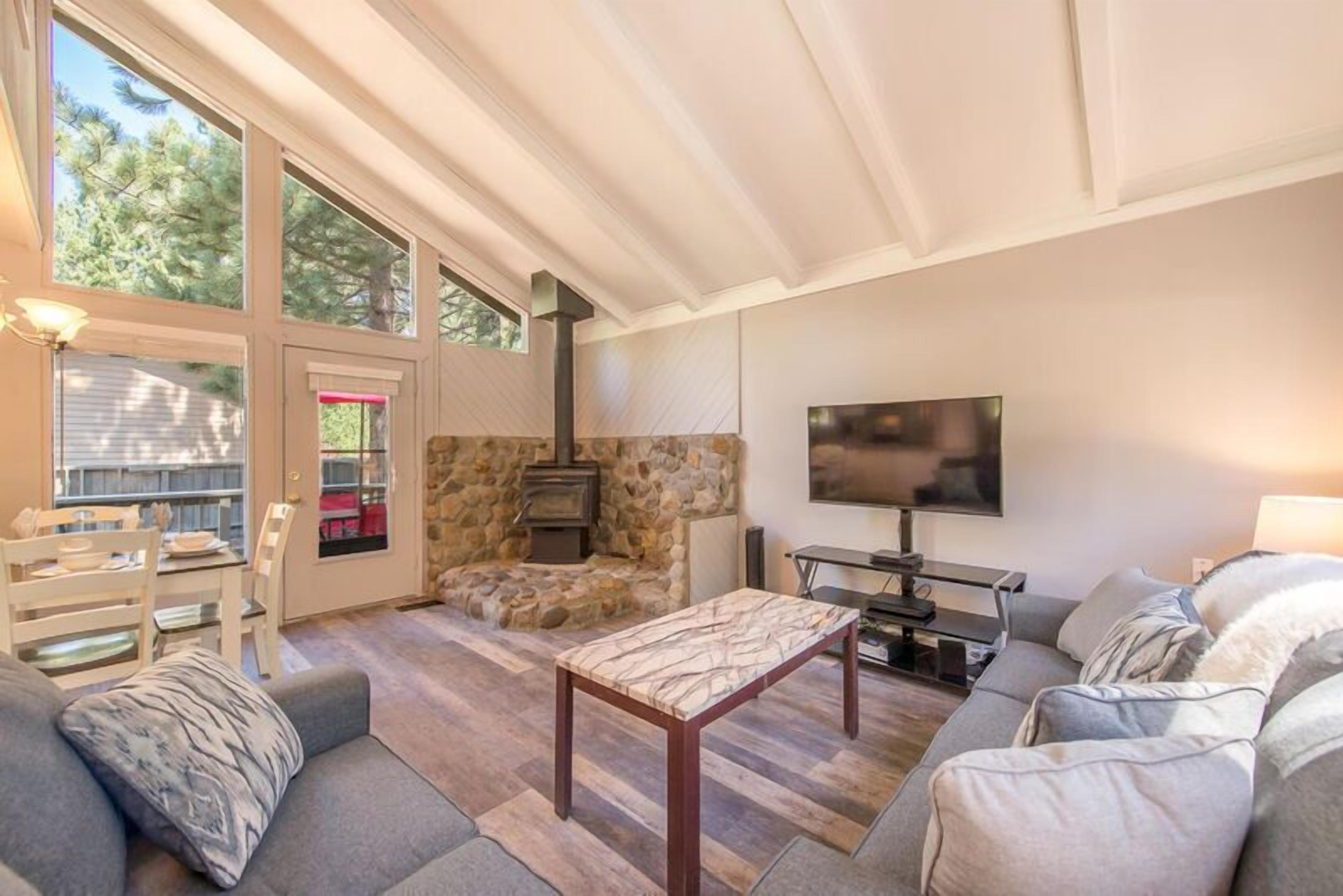 Una sala de estar acogedora con chimenea de piedra, un televisor de pantalla plana y un comedor con mesa y sillas.