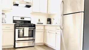 Una cocina con armarios blancos, horno de acero inoxidable y refrigerador.