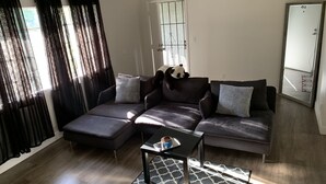 Una sala de estar moderna con un sofá seccional, una mesita de centro y un ventanal con cortinas.