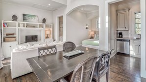 A modern living room with a dining table, wicker chairs, a sofa, and a TV.