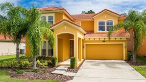 A two-story house with a yellow facade, a red-tiled roof, and a garage. - Life of Luxury by VillaDirect (Kissimmee)