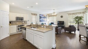A spacious kitchen with white cabinets, a granite countertop, and stainless steel appliances. - Life of Luxury by VillaDirect (Kissimmee)