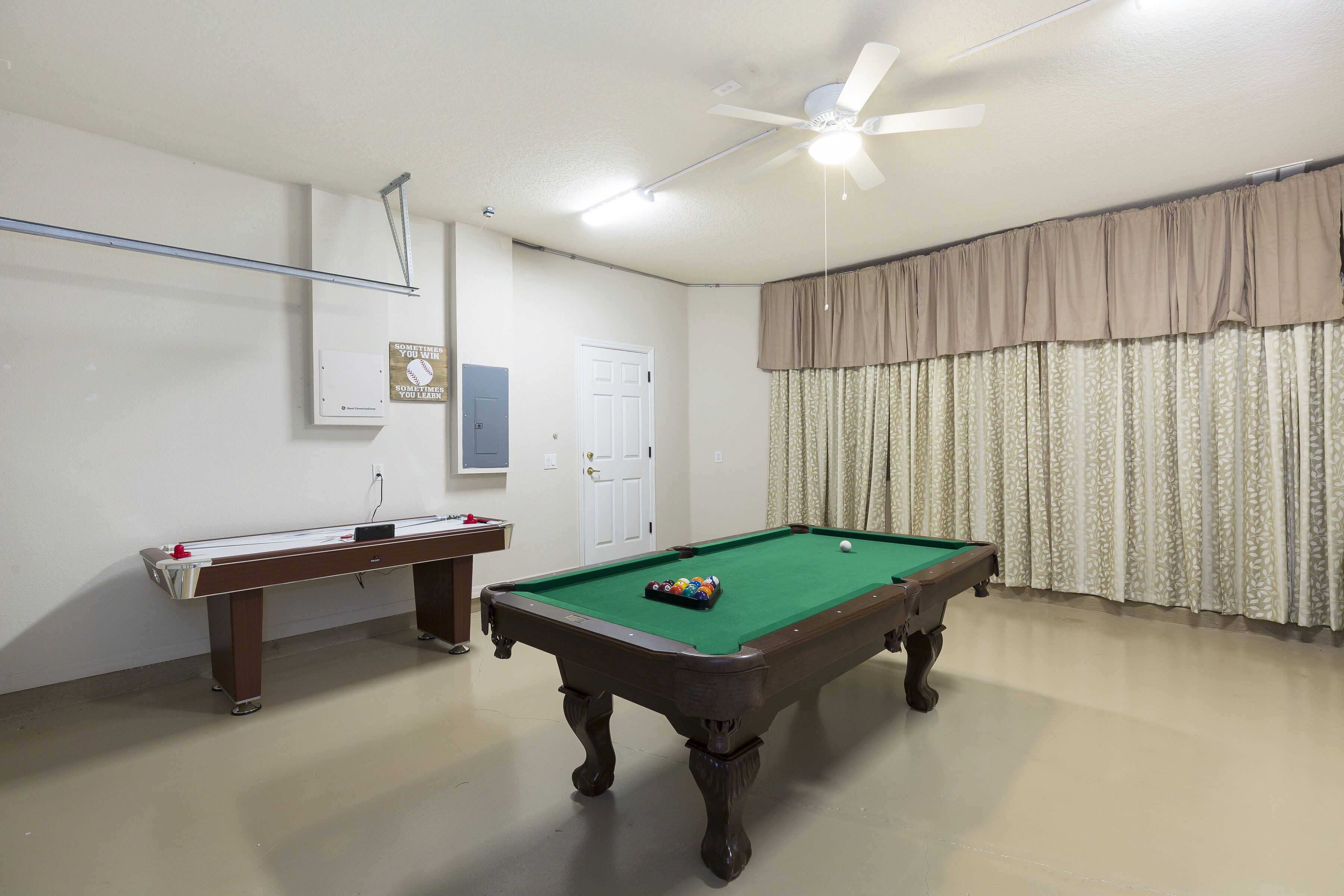 A pool table with a green felt surface, a pool cue, and a set of balls in the center.