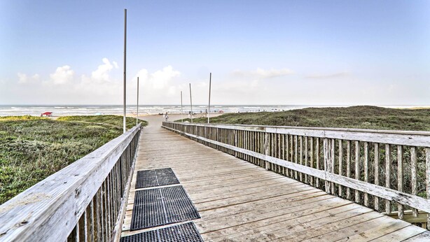 En träpromenad som leder till en strand med klar himmel.