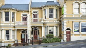 Un bâtiment jaune doté de grandes baies vitrées et d’un balcon.