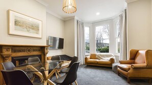 Un salon moderne avec une table à manger au plateau en verre, des canapés en cuir et une cheminée.