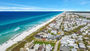 A coastal residential area with houses, a beach, and a clear blue sky.