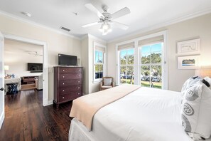 Quarto com cama grande, penteadeira, televisão e vista para o exterior.