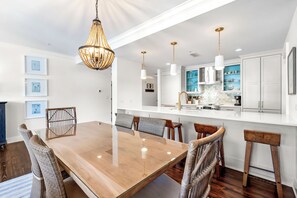 Uma sala de jantar moderna com mesa de madeira, cadeiras de vime e iluminação pendente.