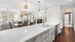 A spacious kitchen with a large island, white cabinetry, and pendant lighting.
