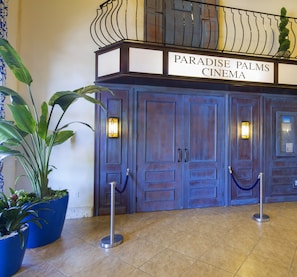 Enter Paradise Palms Cinema through its grand entrance, featuring a classic design and beautiful potted plants.