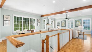 A spacious room with a wooden staircase, large windows with shutters, and a ceiling fan. - Knoepp Cottage & Carriage House - Spectacular Gulf Views, South of 30A (Rosemary Beach)