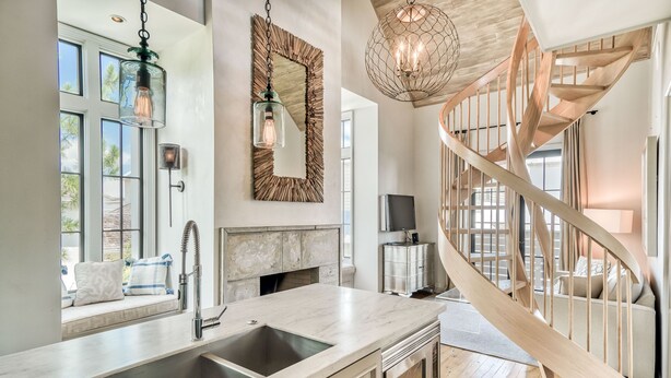 Une cuisine moderne dotée d’un grand îlot central, d’un escalier en bois et d’un grand miroir.