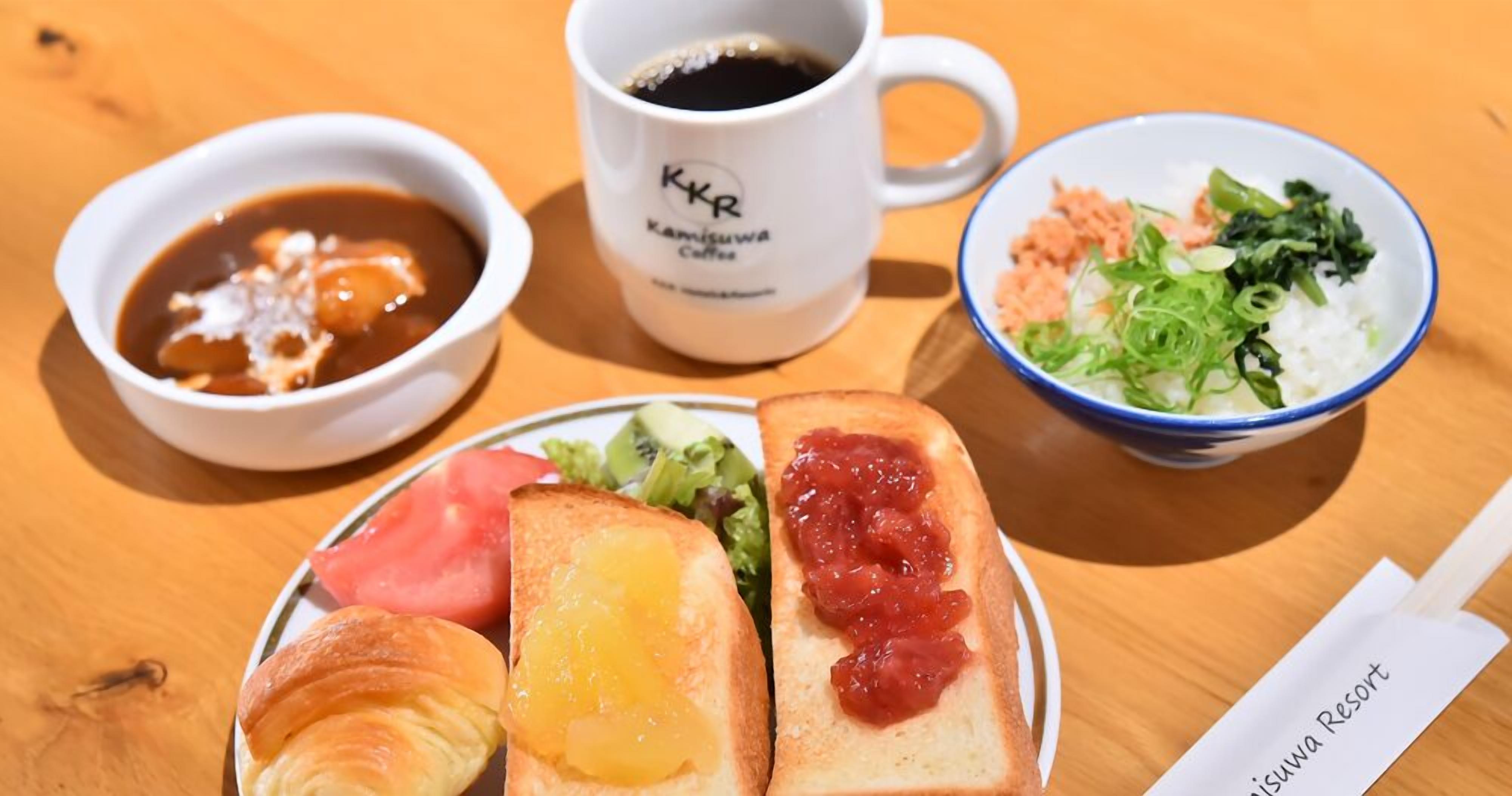 A meal with bread, soup, and a bowl of salad on a wooden table.