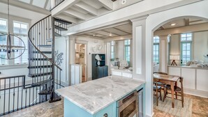 A spacious kitchen with a marble island, a built-in oven, and a dining area with a wooden table and chairs. - Beach Bungalow Cottage - Nestled behind the Dunes! Gulf Views! FREE GYM/TENNIS (Rosemary Beach)