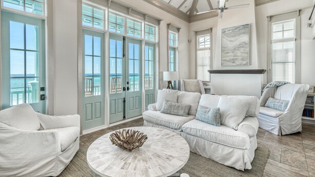 A spacious living room with a large window, a round coffee table, and a white sofa. - Beach Bungalow Cottage - Nestled behind the Dunes! Gulf Views! FREE GYM/TENNIS (Rosemary Beach)