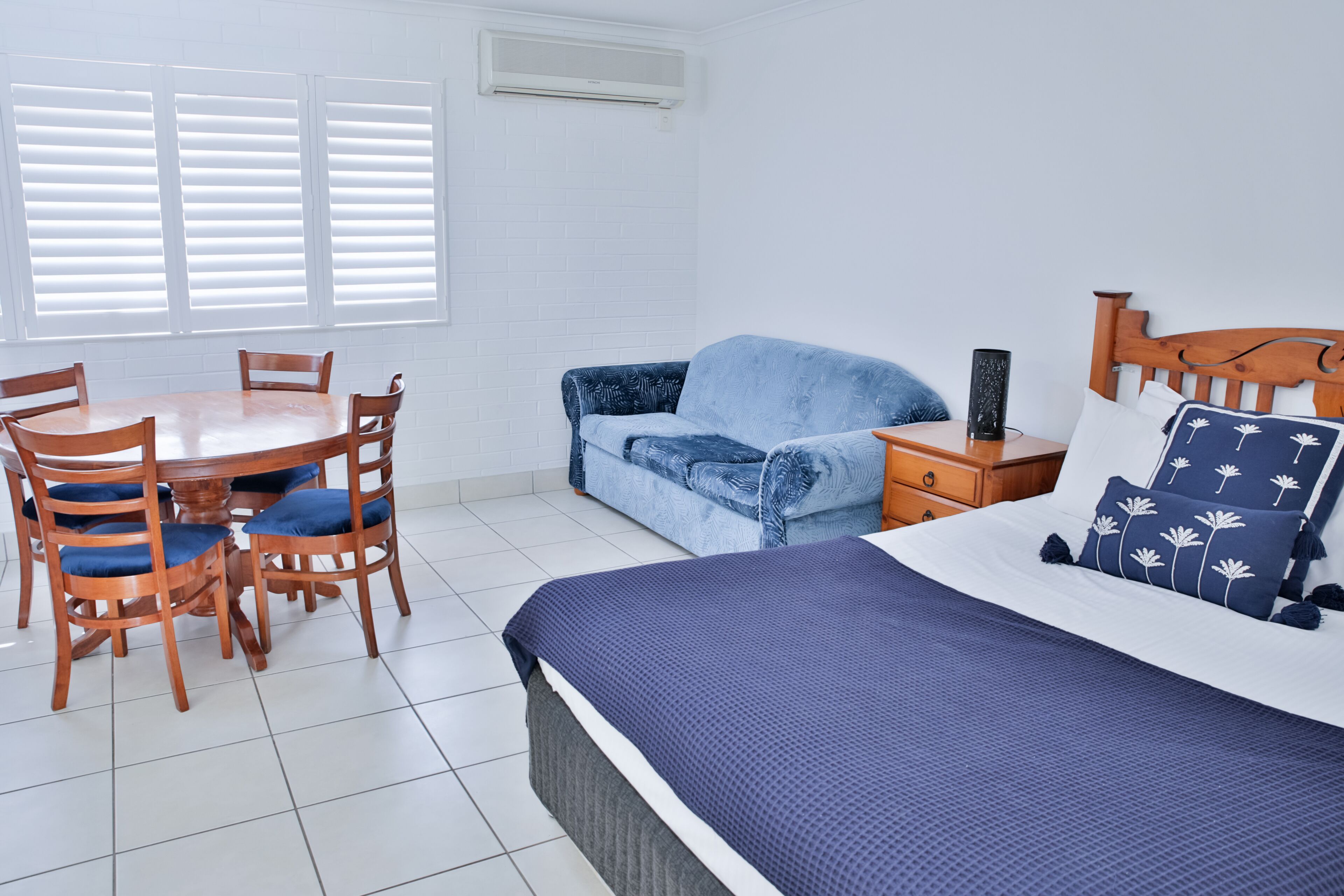 Une chambre à coucher avec un lit, une table en bois avec des chaises, un canapé et une table de chevet avec une lampe.
