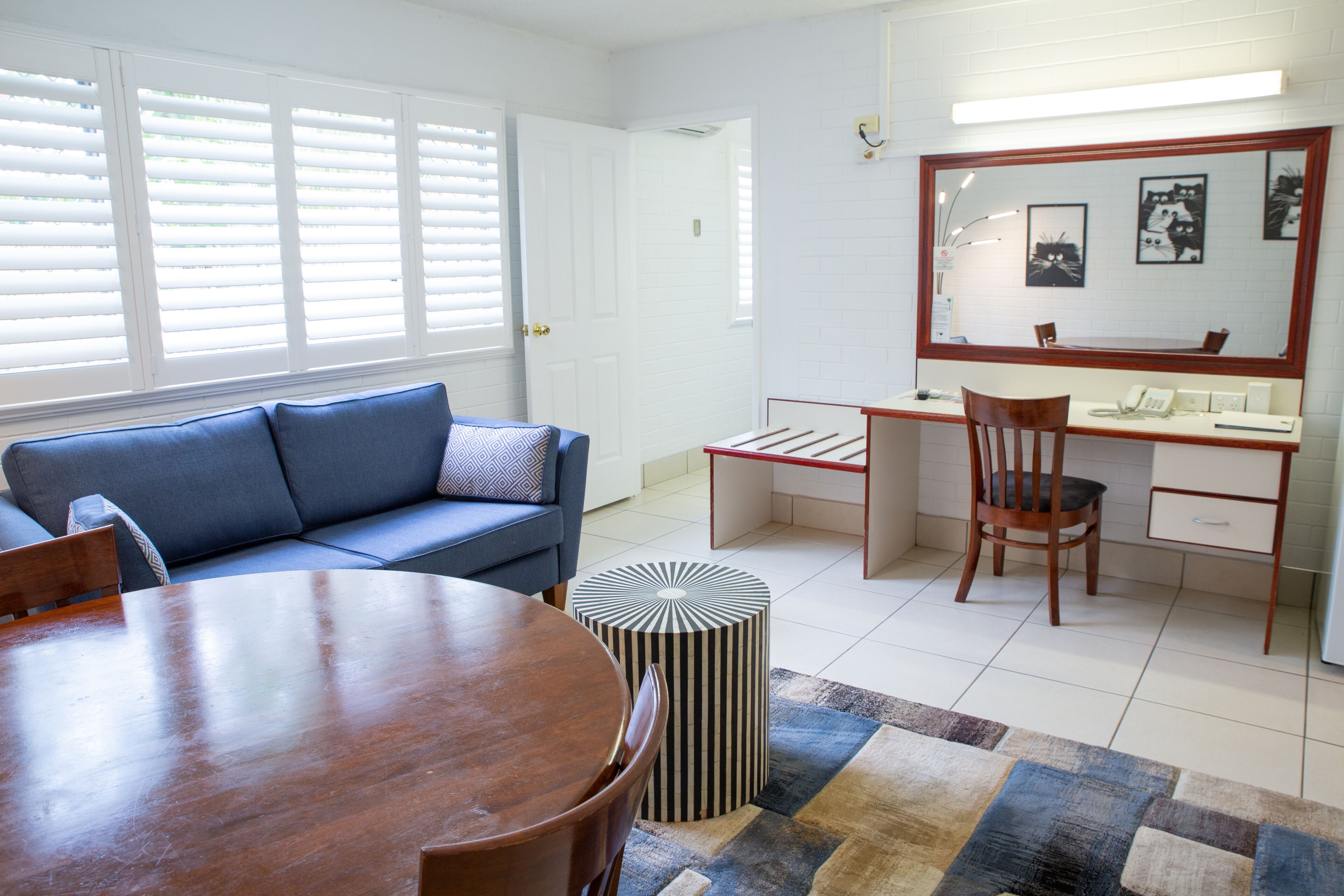 Una sala de estar moderna con un sofá azul, una mesa de comedor de madera y un escritorio con una silla.