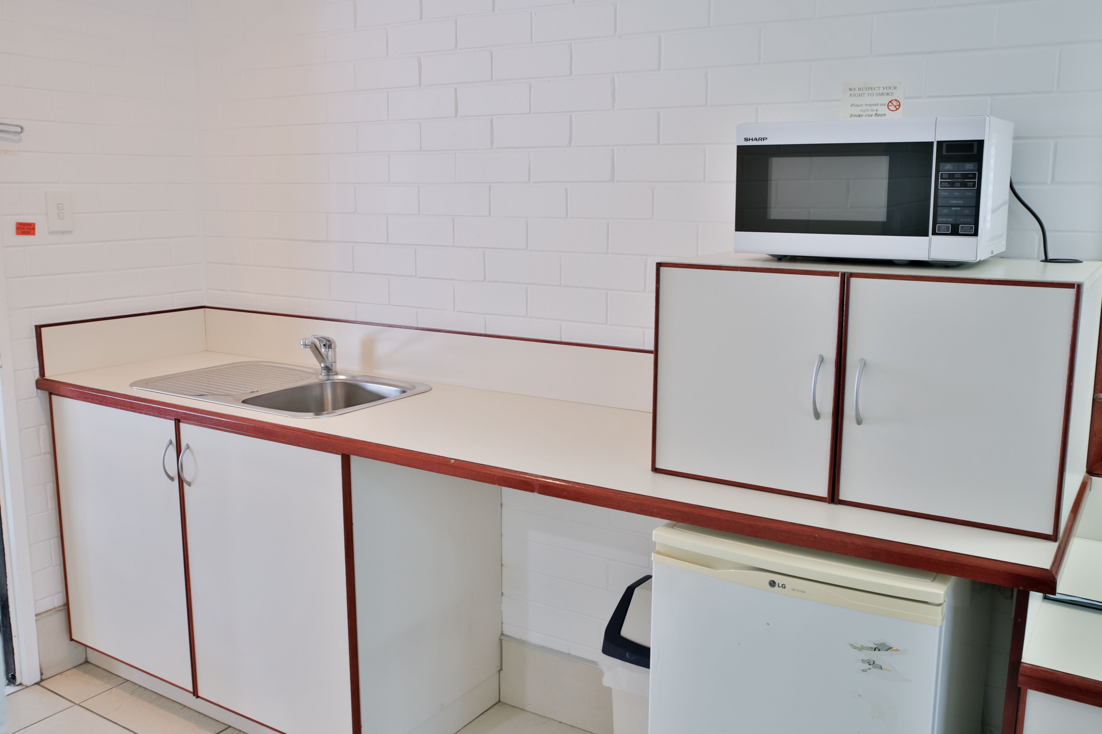 Una cocina compacta con microondas, fregadero y armarios.