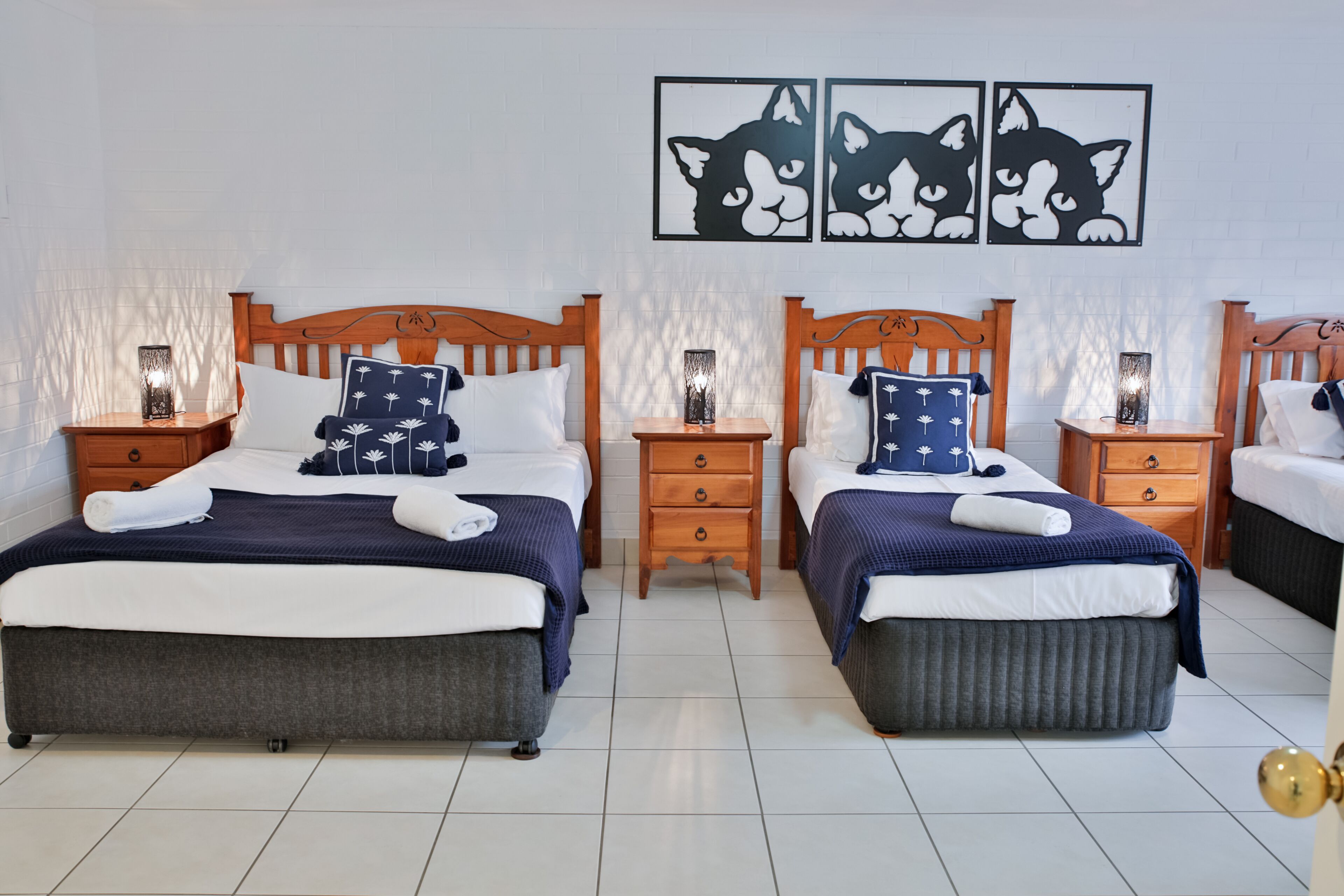 Habitación de hotel con dos camas, cabeceros de madera y mesitas de noche con lámparas.