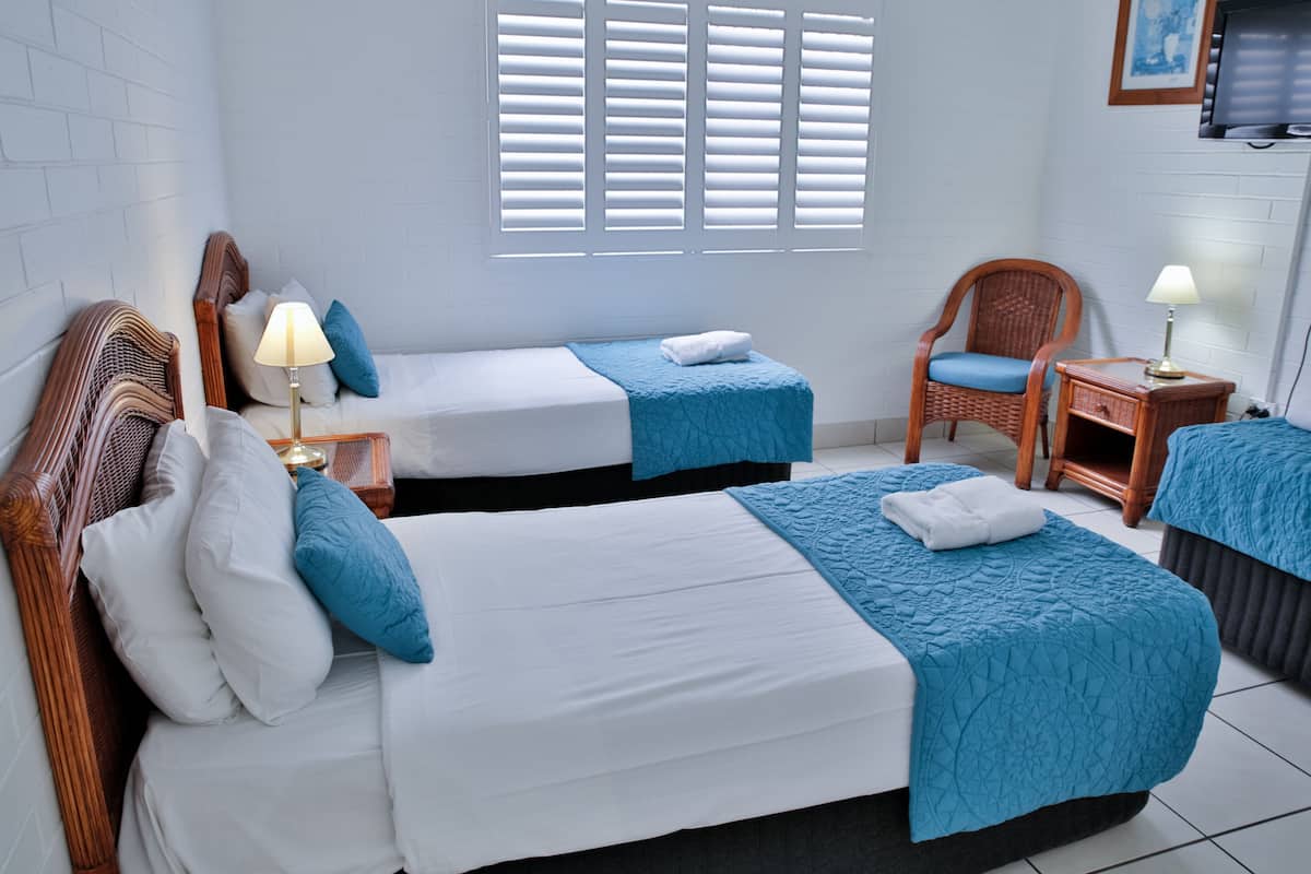 A hotel room with two beds, a chair, a nightstand, and a TV.