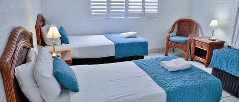 A hotel room with two beds, a chair, a nightstand, and a TV.