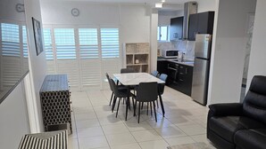A modern kitchen with a refrigerator, microwave, and stove. There is a dining area with a table and chairs. - Central Park Motel (Allenstown)