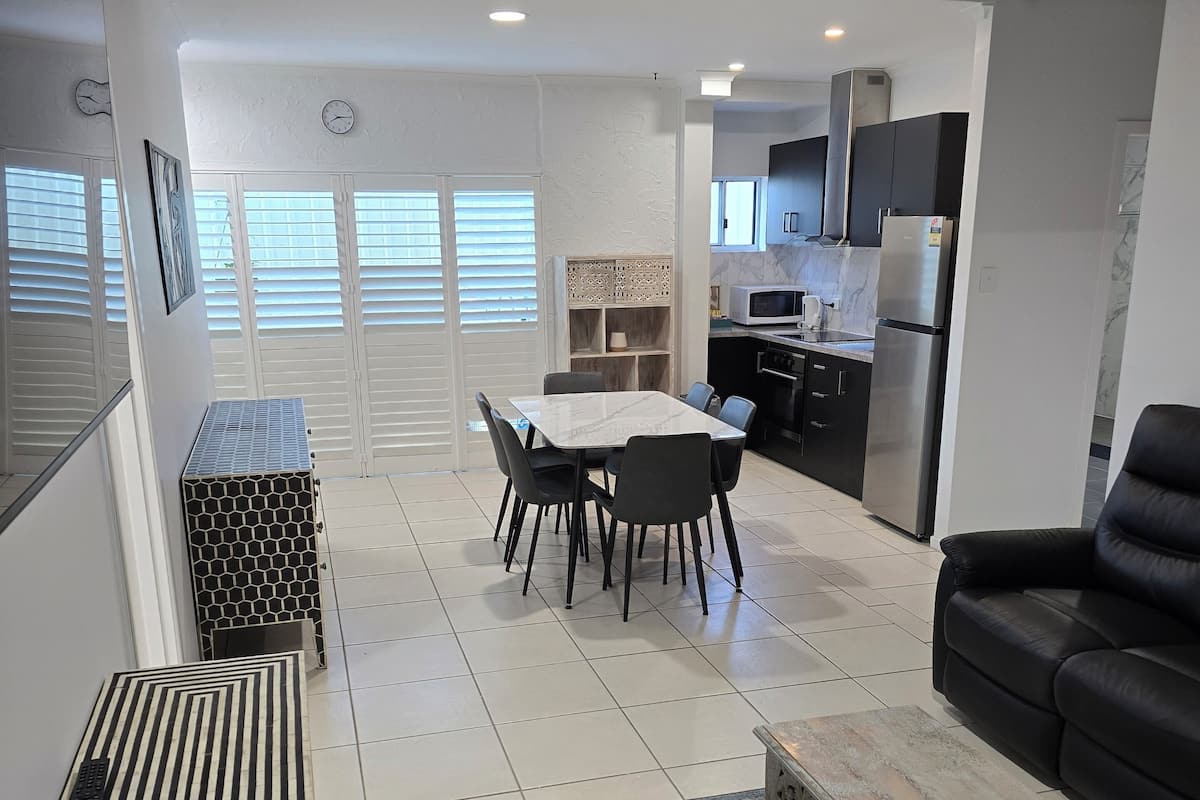 A modern kitchen with a refrigerator, microwave, and stove. There is a dining area with a table and chairs.