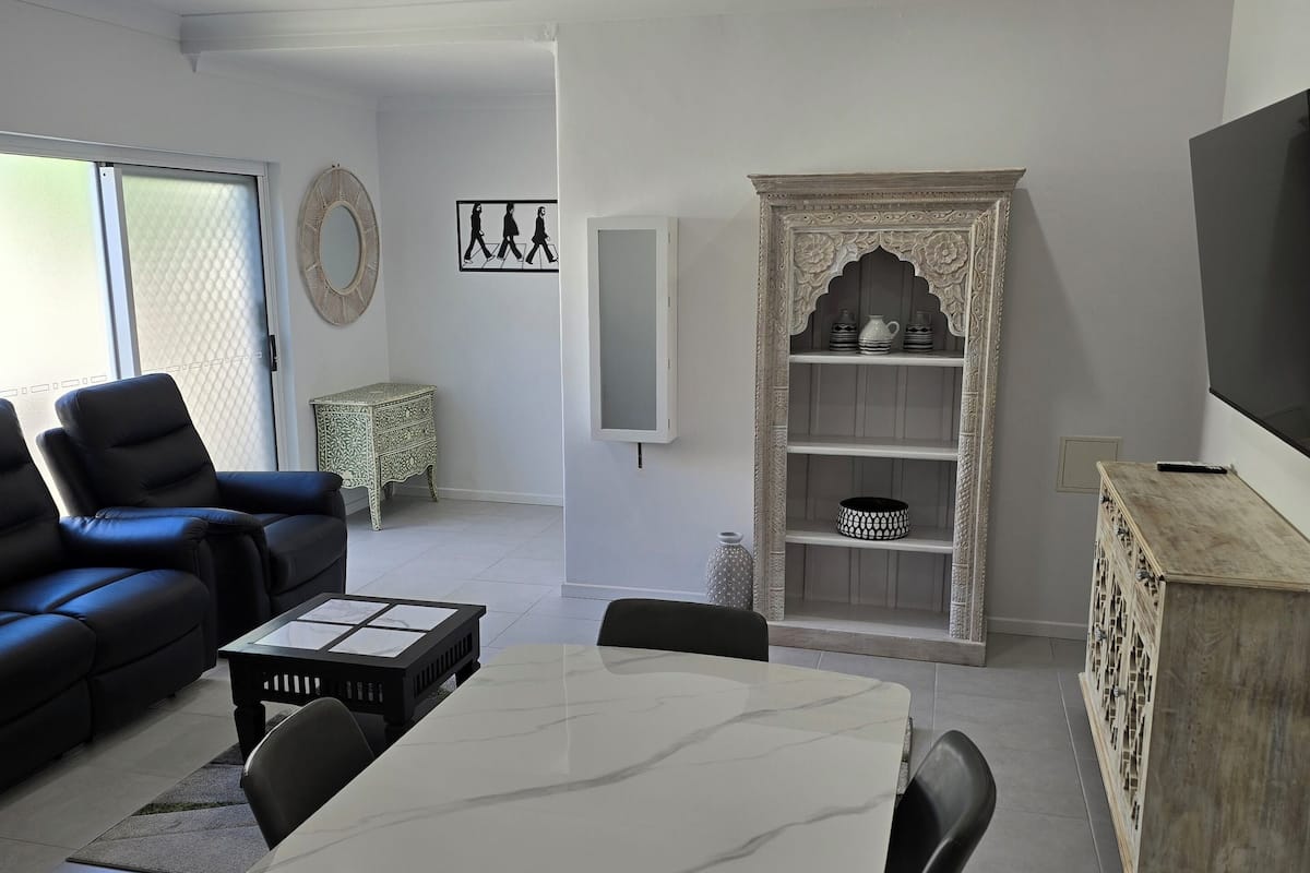 A modern living room with a dining area, a sofa, a TV, and decorative items.