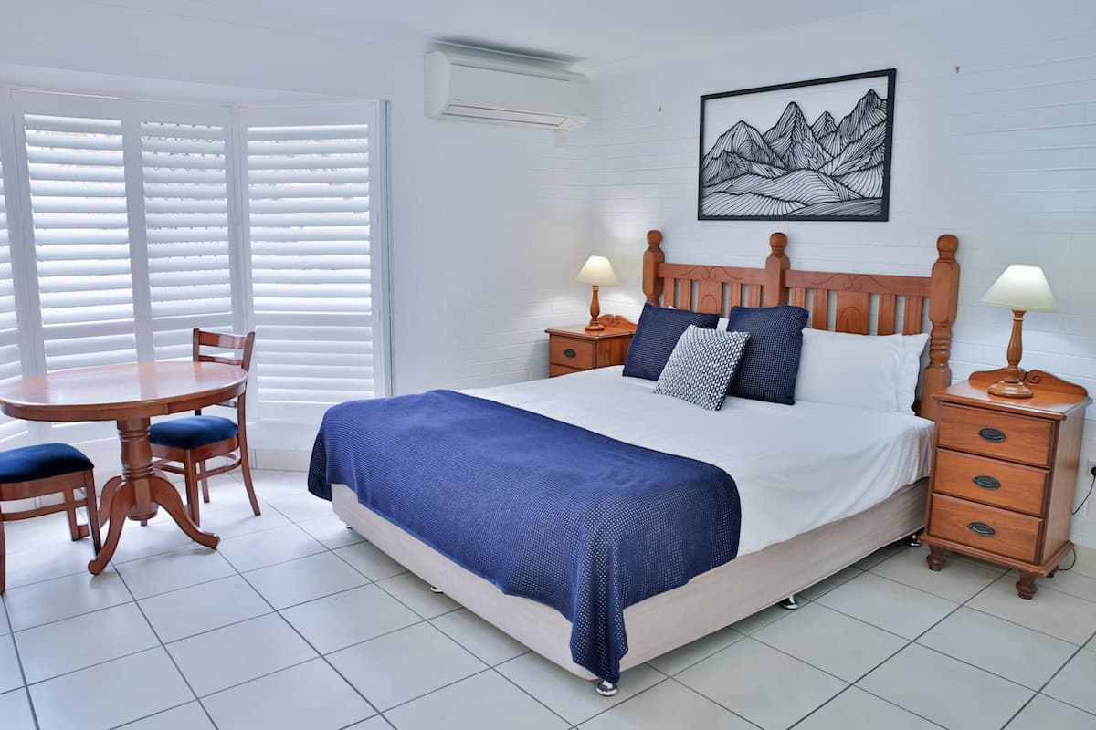 A neatly arranged bedroom with a bed, bedside tables, a chair, and a table.