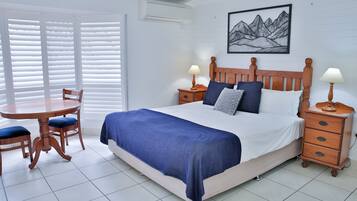 A neatly arranged bedroom with a bed, bedside tables, a chair, and a table.