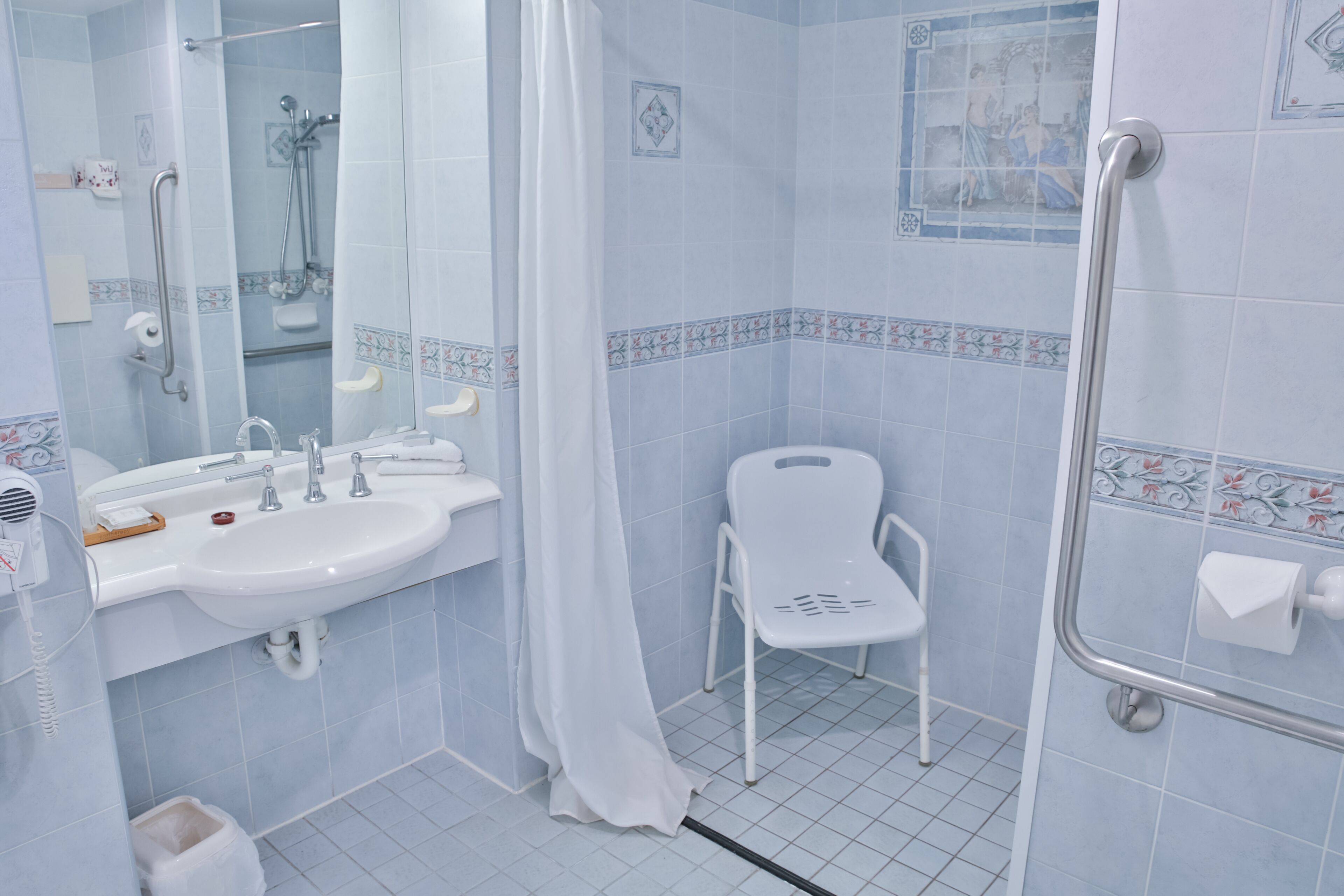 A bathroom with a sink, mirror, shower, and toilet.