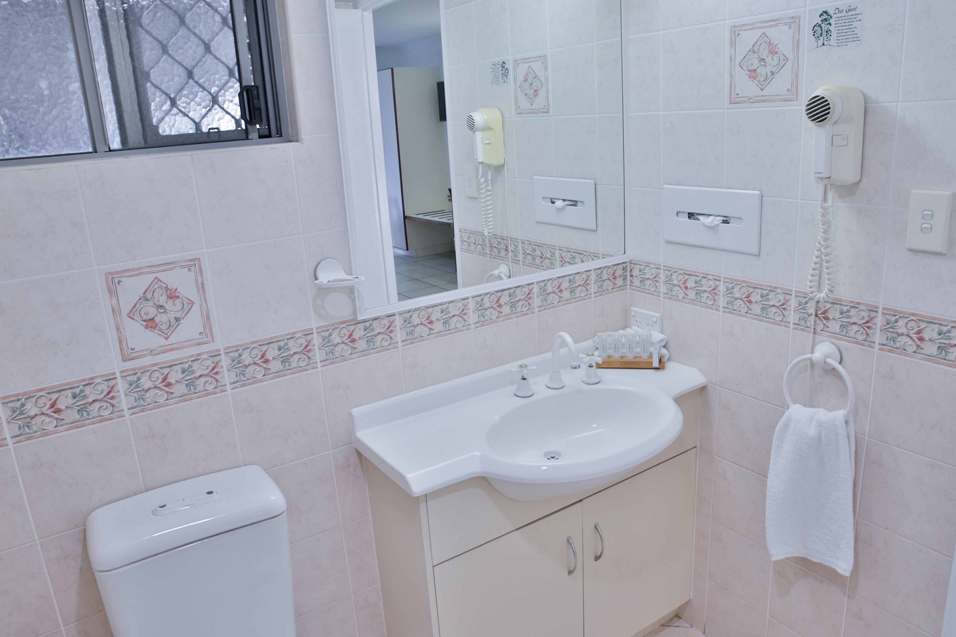 A bathroom with a toilet, sink, and towel rack.