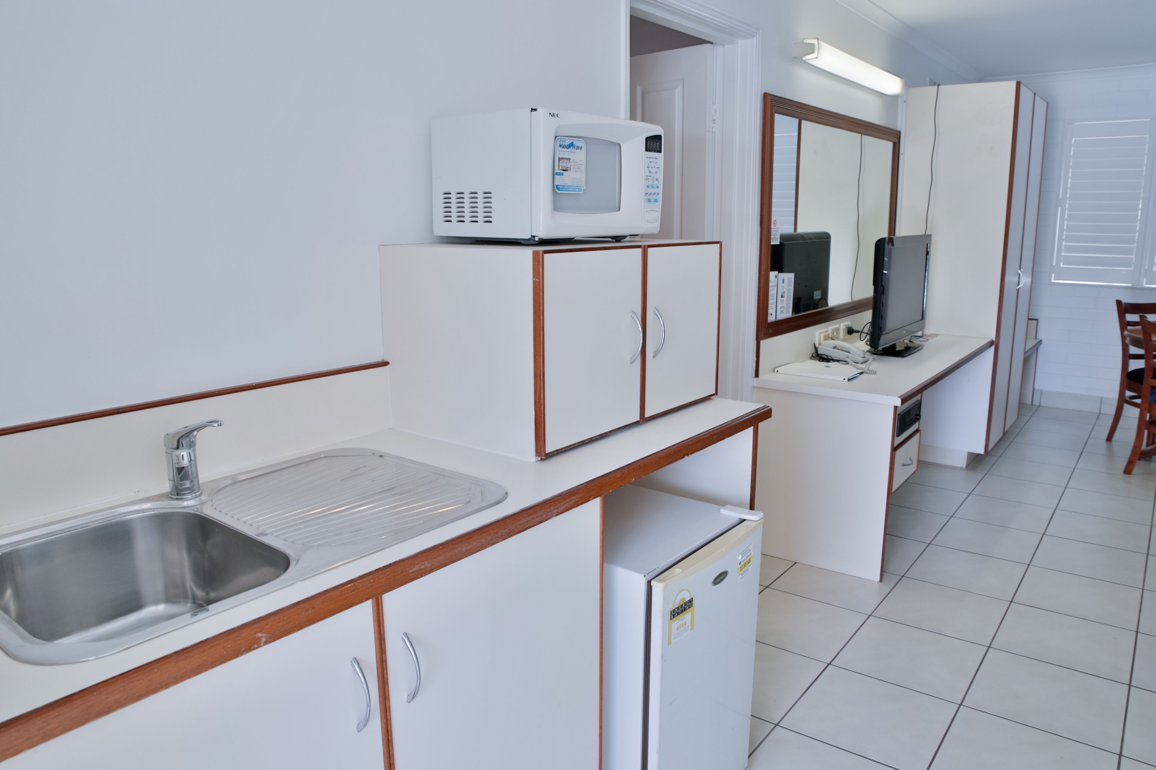 A compact kitchenette with a built-in microwave, a sink, and a refrigerator.