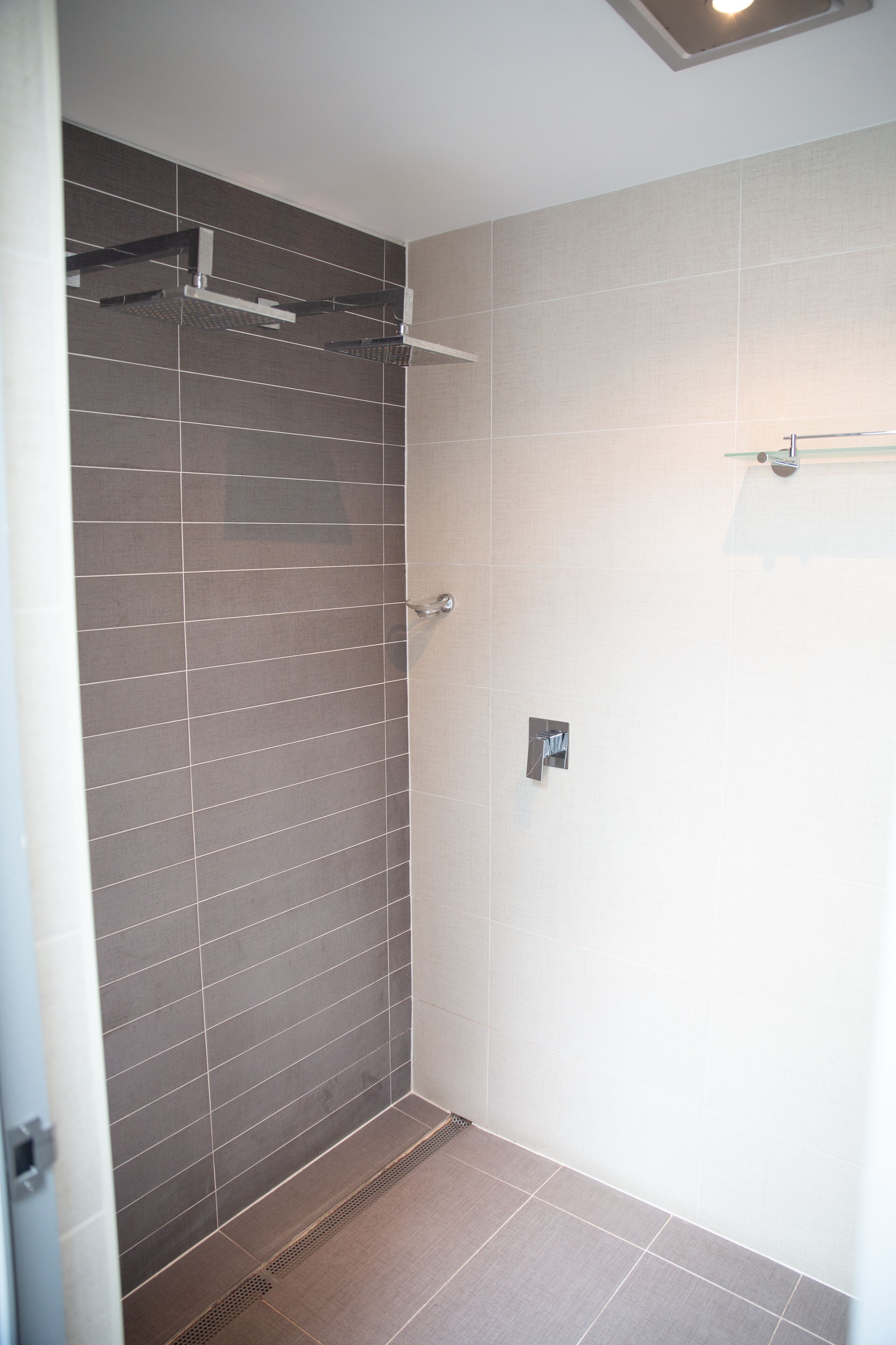 A modern bathroom with a shower area, tiled walls, and a visible shower control panel.