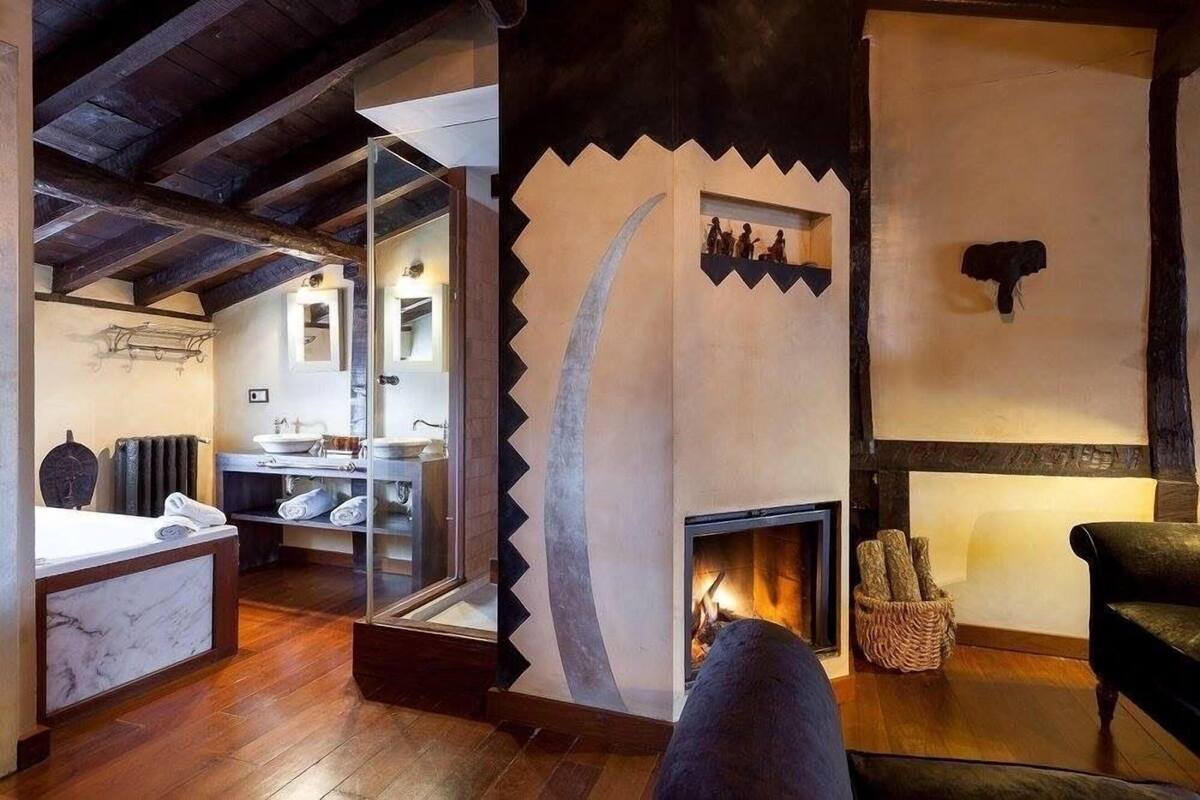 A rustic interior with a fireplace, wooden beams, and a stone wall.