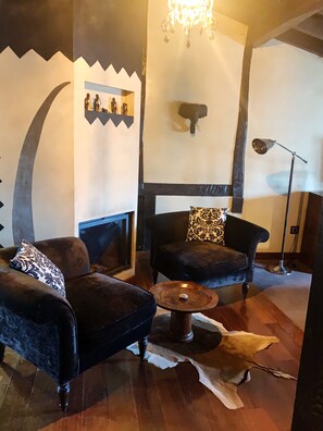 Una sala de estar acogedora con dos sofás oscuros, una mesa de centro redonda y una chimenea.