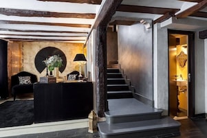 Un interior moderno con una escalera, un sofá negro y un elemento decorativo en la pared.