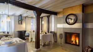 A dining area with a fireplace, wooden beams, and a view of the dining room. - Hotel Boutique Valle de Oca (Valle de Oca)