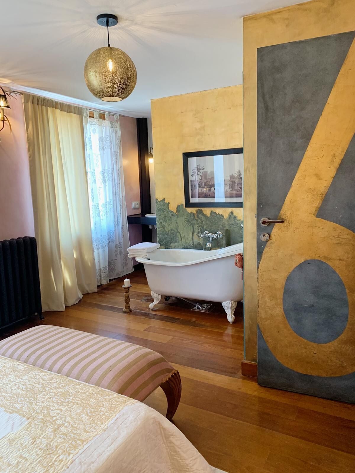 Une chambre avec un grand lit, une baignoire de style ancien et un grand chiffre « 6 » peint sur le mur.