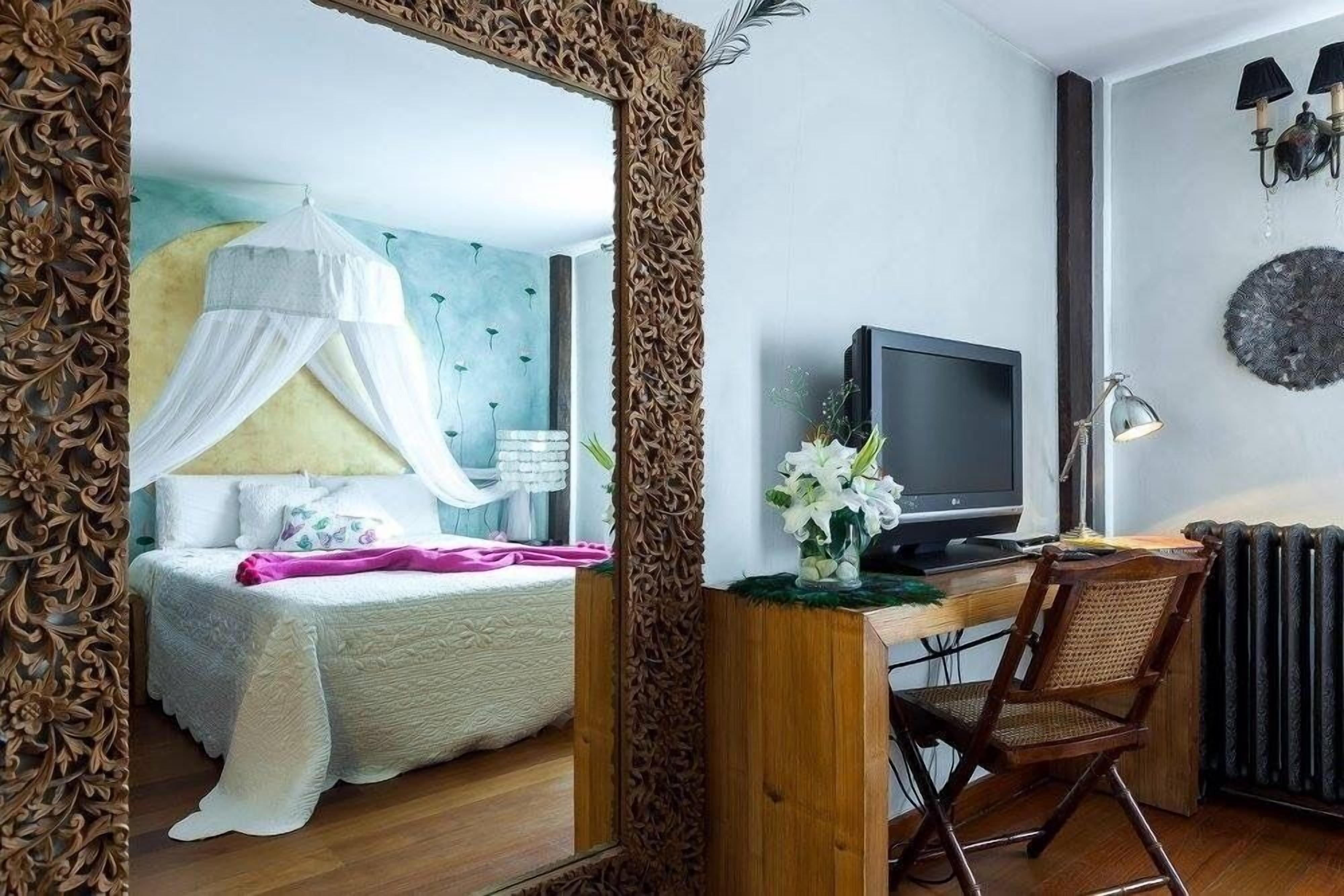 Un dormitorio con cama, mesita de noche, lámpara y un escritorio con silla.