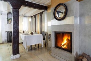 A dining area with a fireplace, a table set for two, and a mirror on the wall.